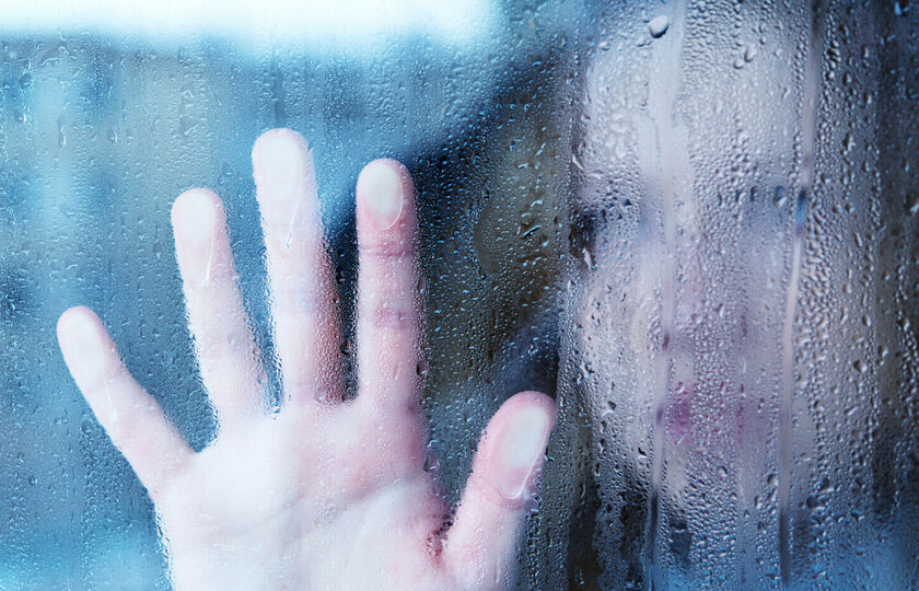 Sad woman looking out of rainy window