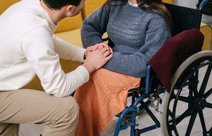 Disabled woman holding hands with able bodied man