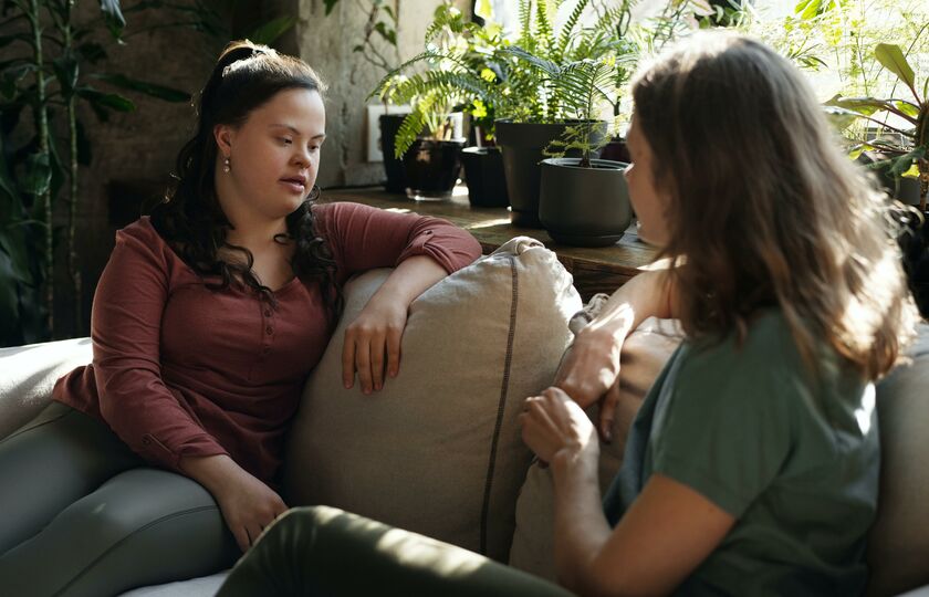 Woman with down syndrome chatting with friend on sofa
