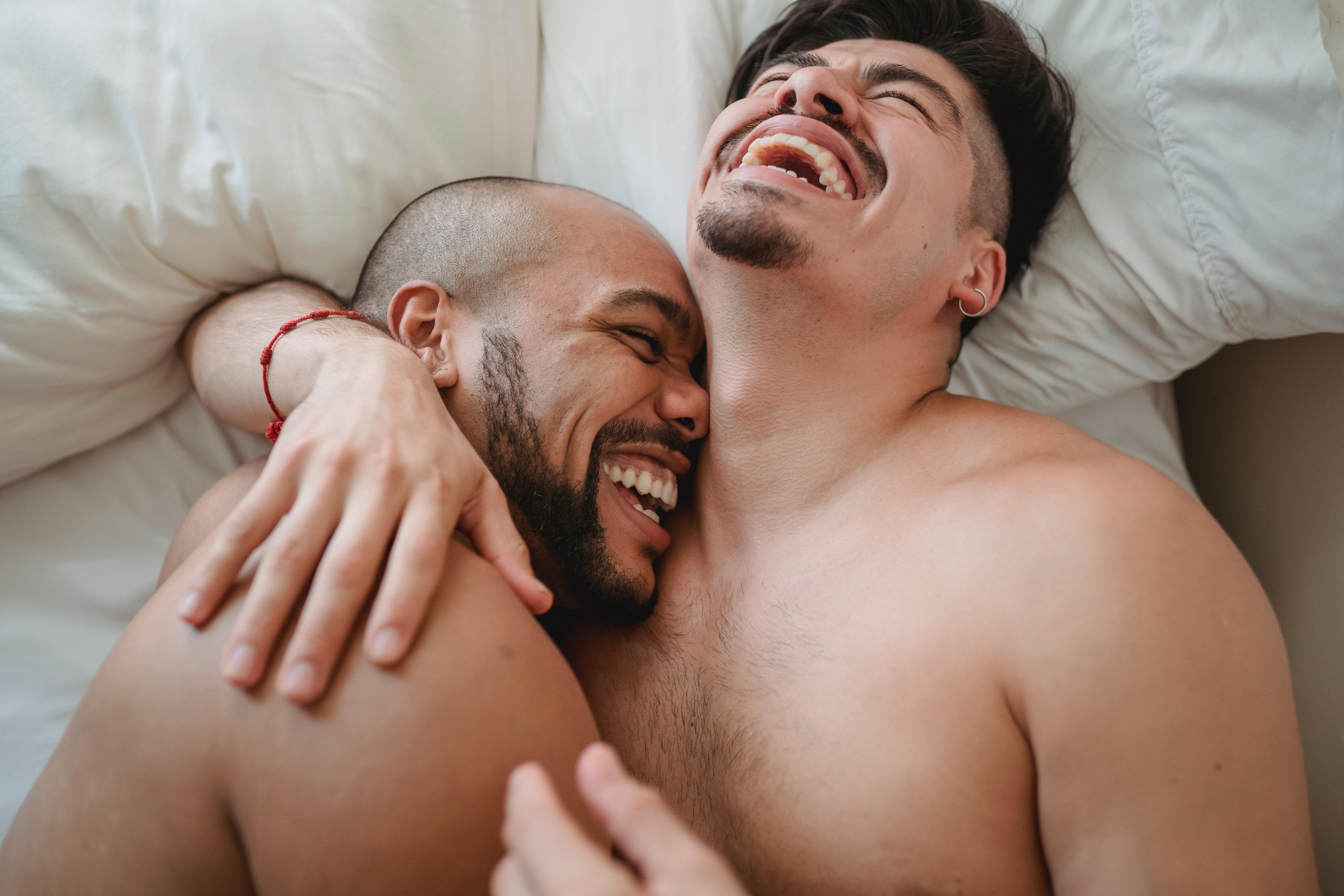Men laughing bed together