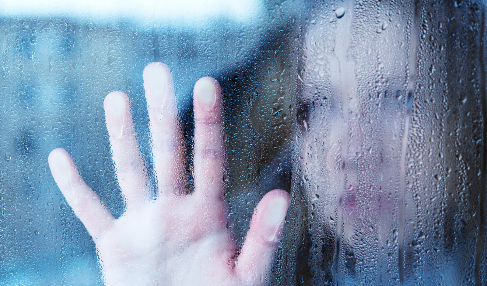 Sad woman looking out of rainy window